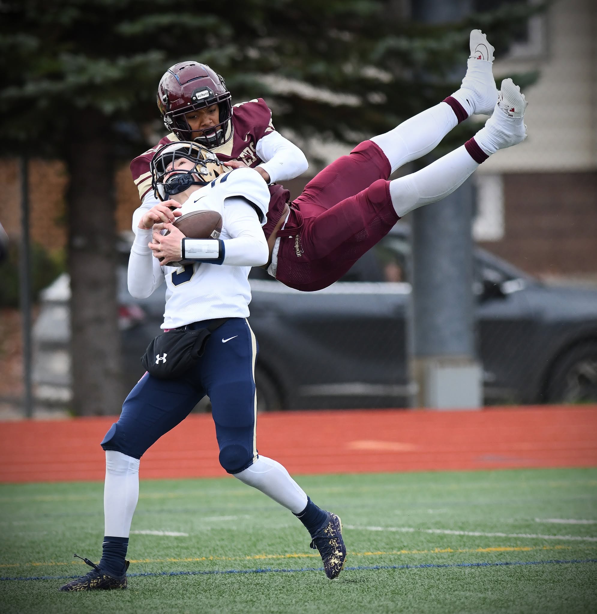 A football defender tackles a ball carrier during a game